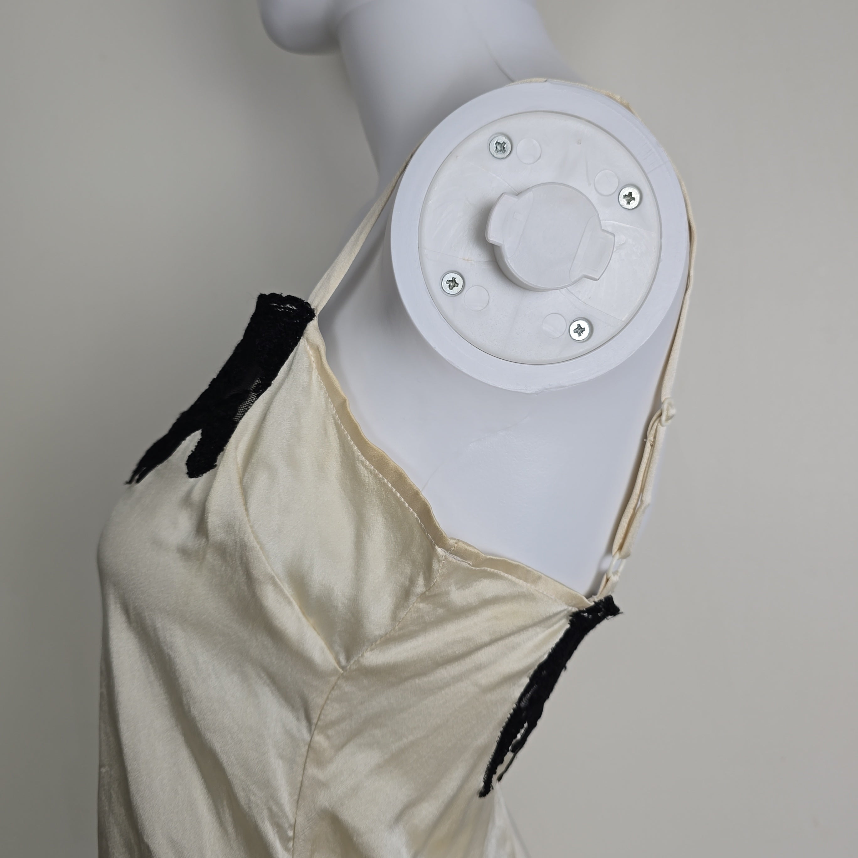 Mannequin wearing a white top with black lace details on a plain background