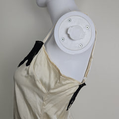 Mannequin wearing a white top with black lace details on a plain background