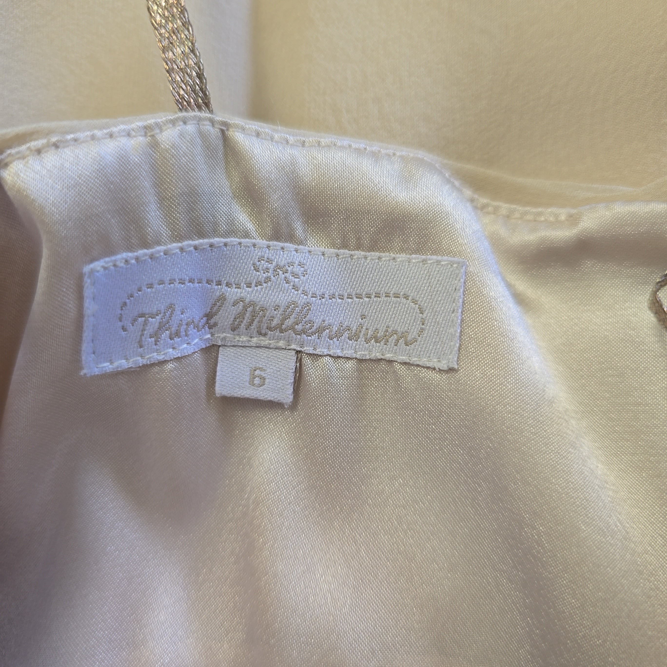 Close-up of a beige top with a label on a beige background