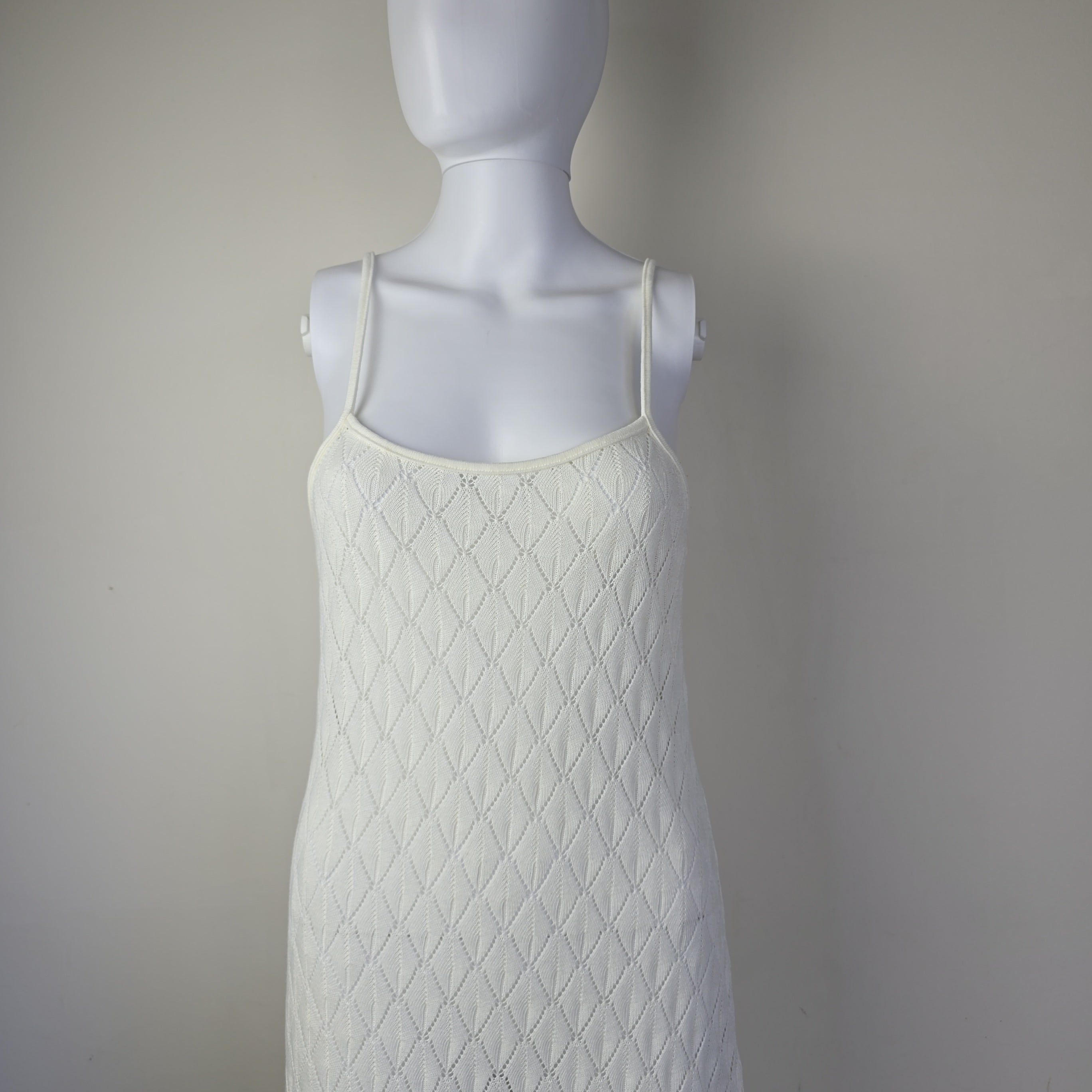 Mannequin wearing a textured white dress against a plain background