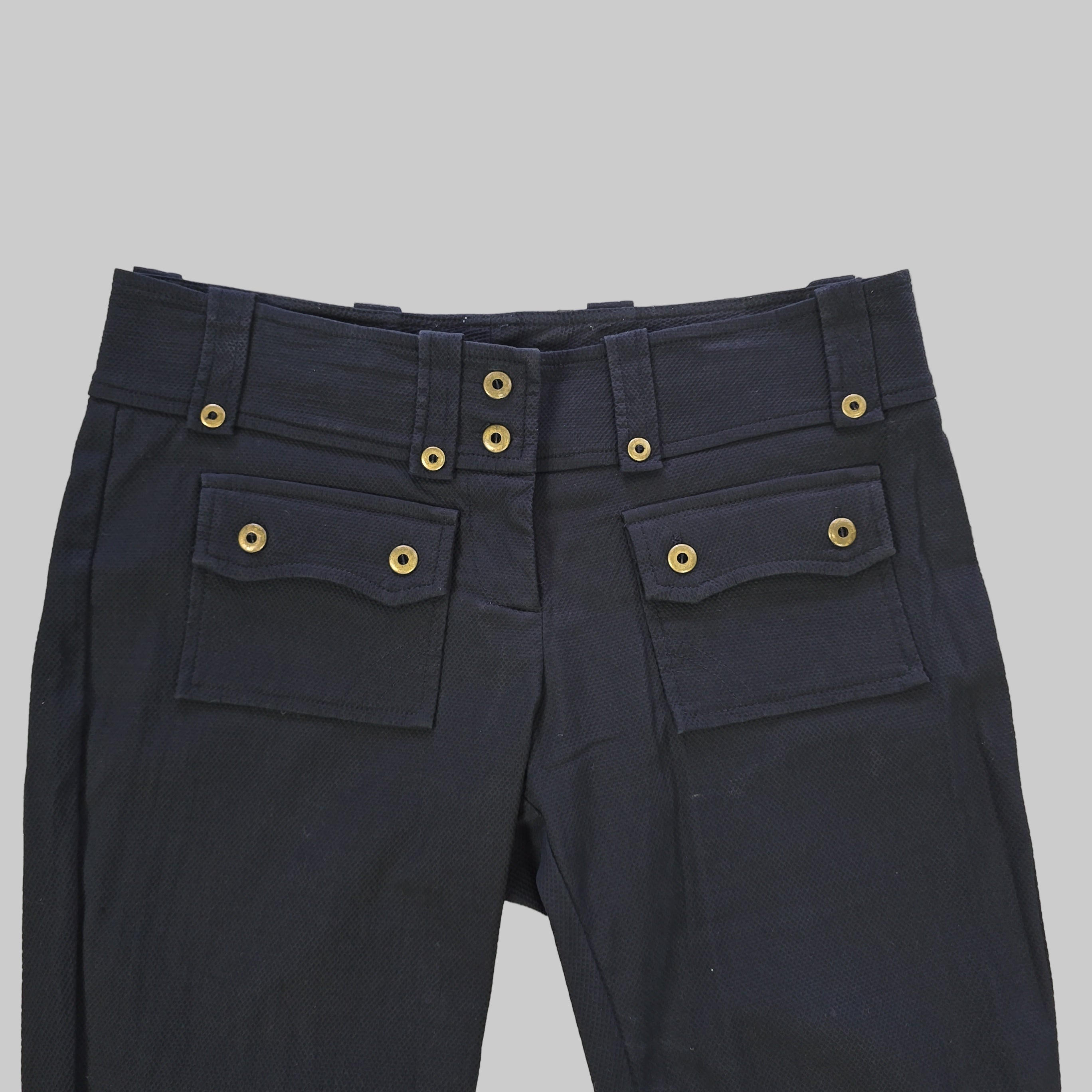 Black pants with gold buttons on a tiled floor