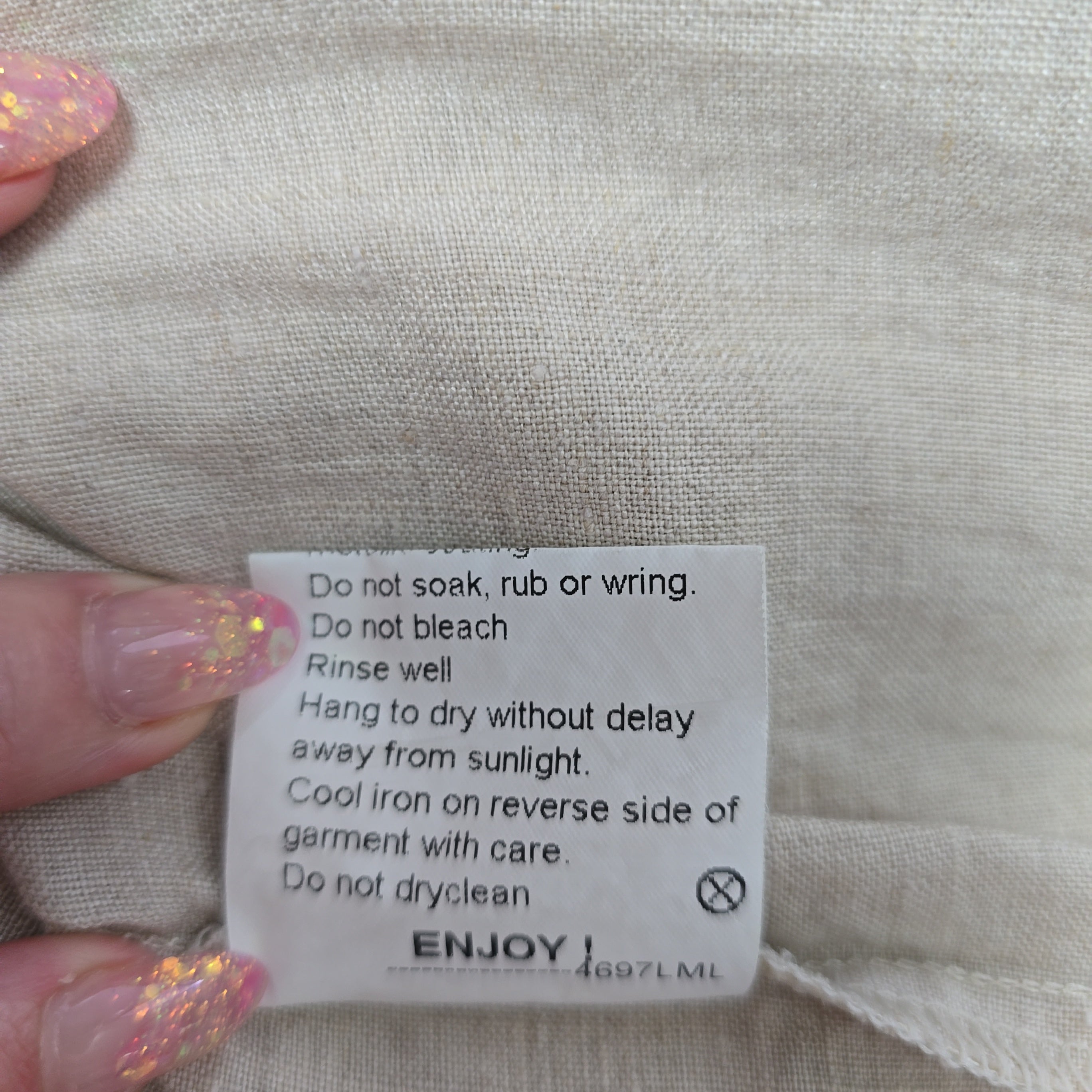 Clothing label on a fabric background with a hand holding it.