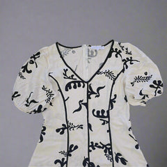White garment with black floral patterns on a tiled floor
