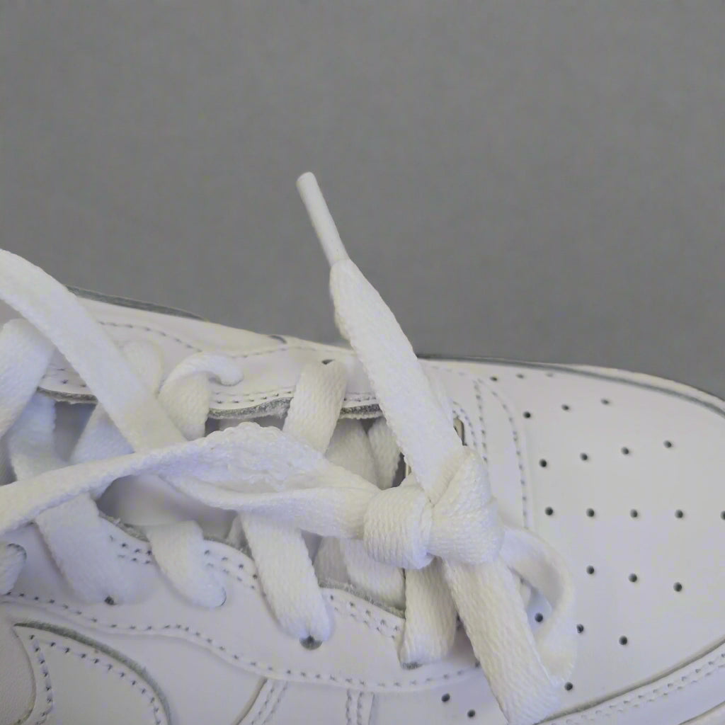 Close-up of a white sneaker with laces on a beige background