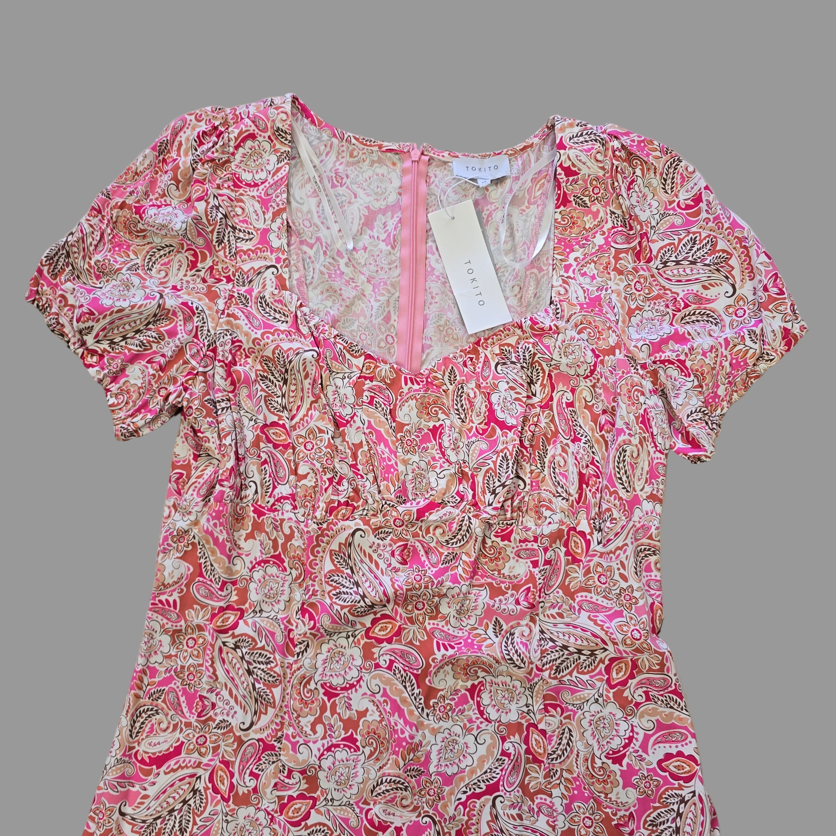 Pink and white patterned garment on a tiled floor with a visible brand tag.