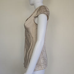 Beige top with a knot detail on alight floor