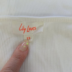 Hand holding a 'Lily Loves' product tag on a textured white background
