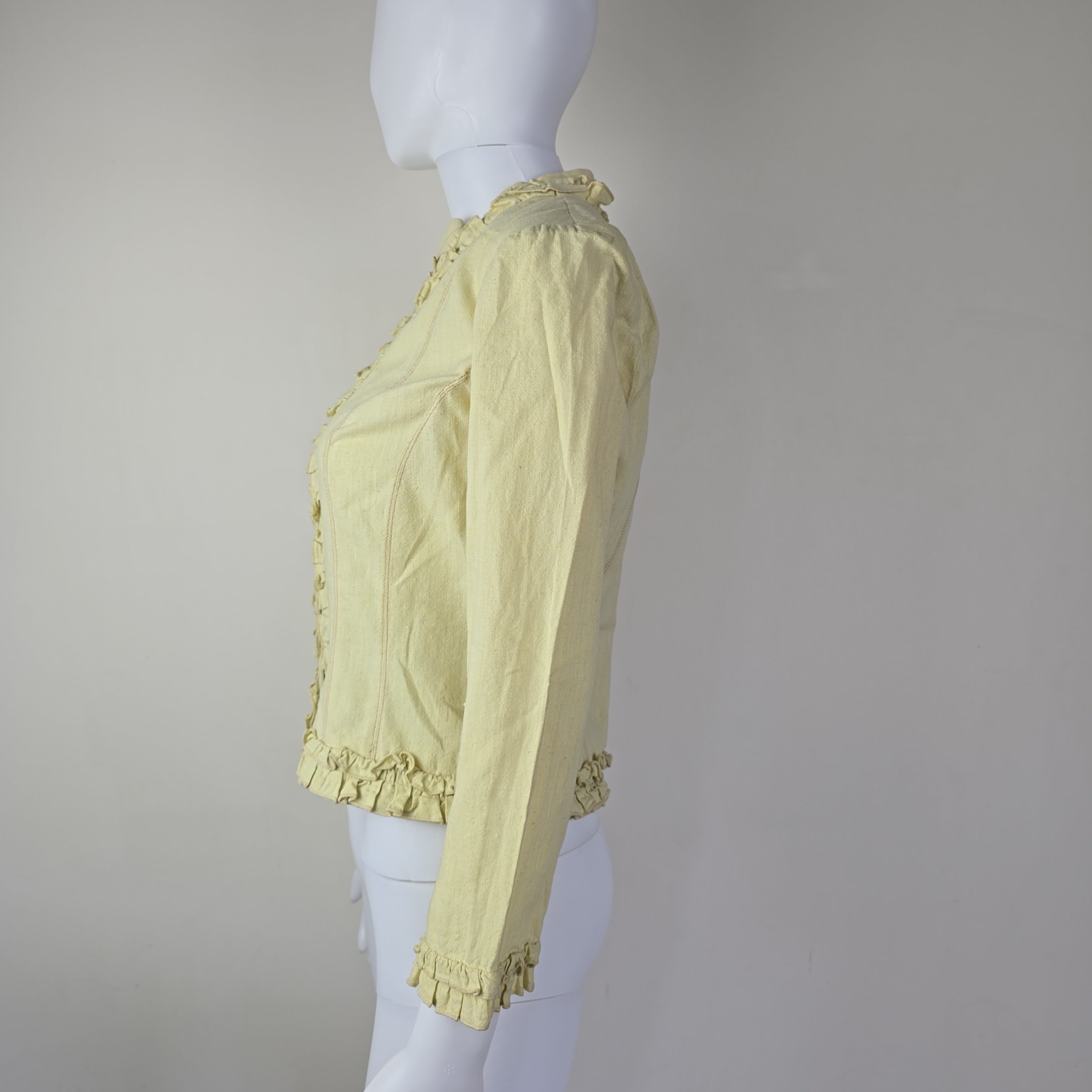 Light yellow jacket with frill details on a light background