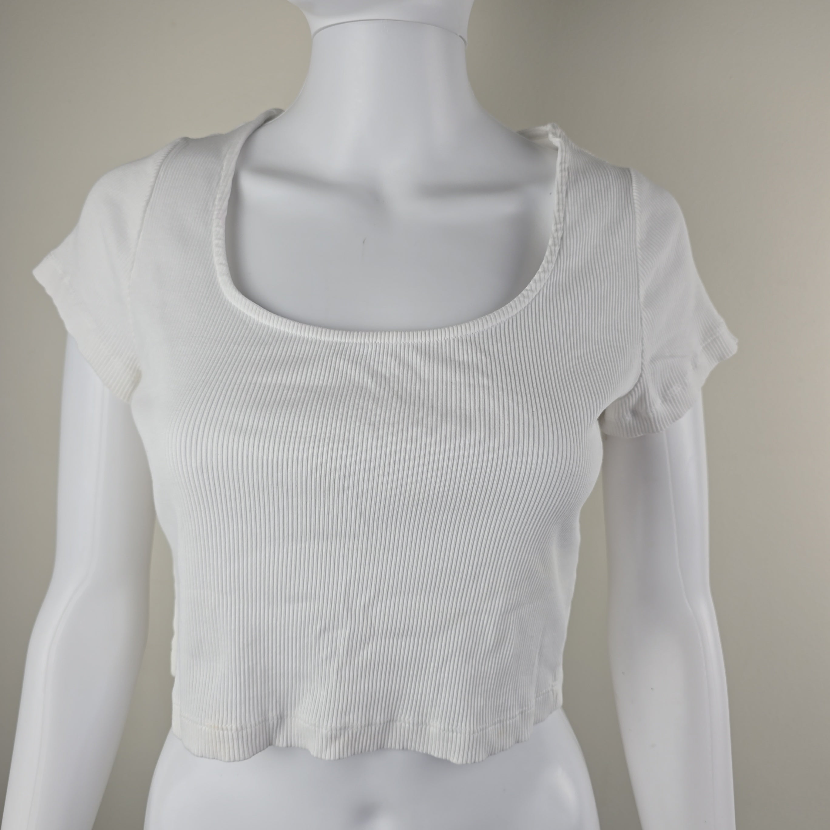 White sleeveless top on a mannequin against a neutral background