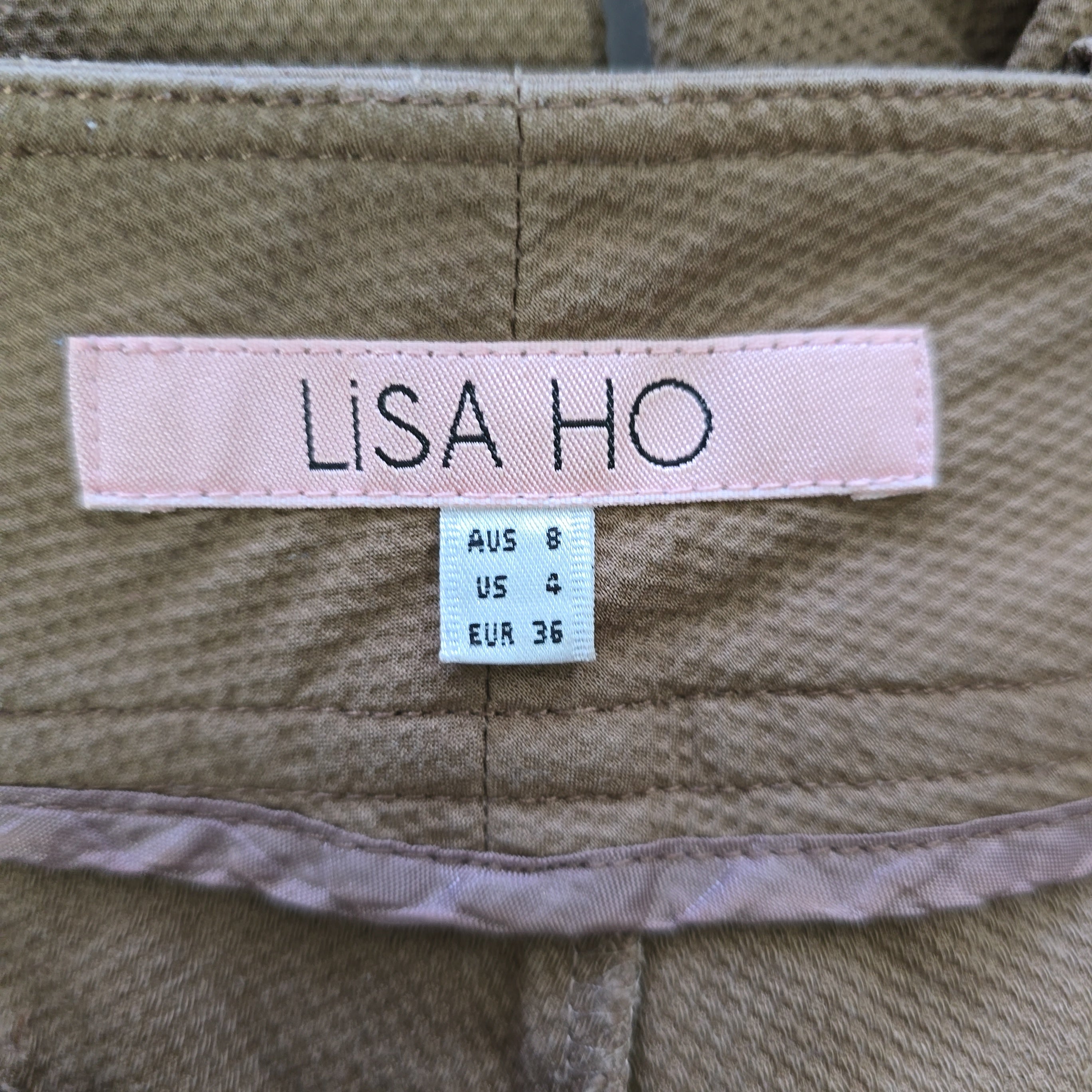 Close-up of a 'LISA HO' label on a garment with size information.