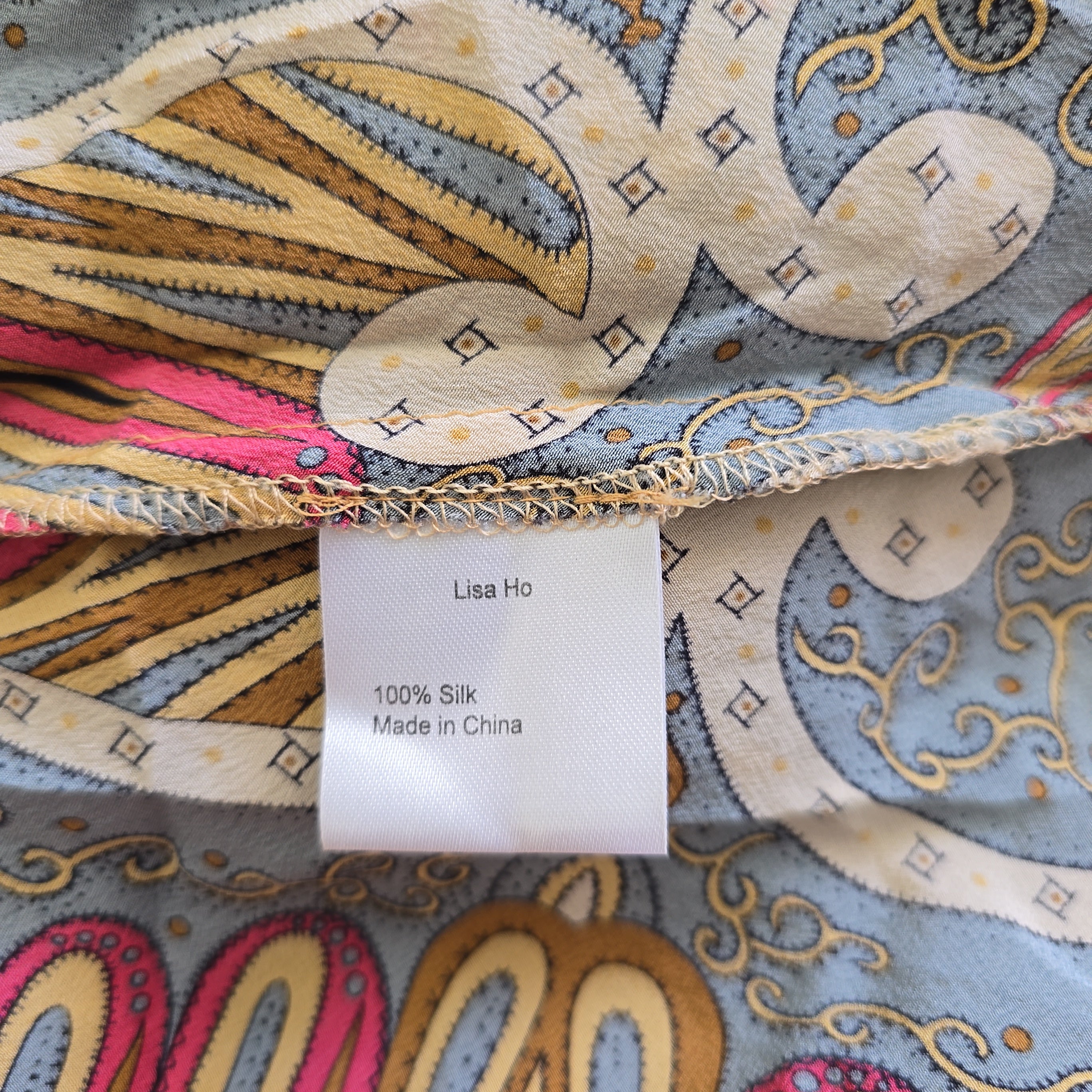 Close-up of a piece of fabric with intricate patterns and a label on a similar patterned background.