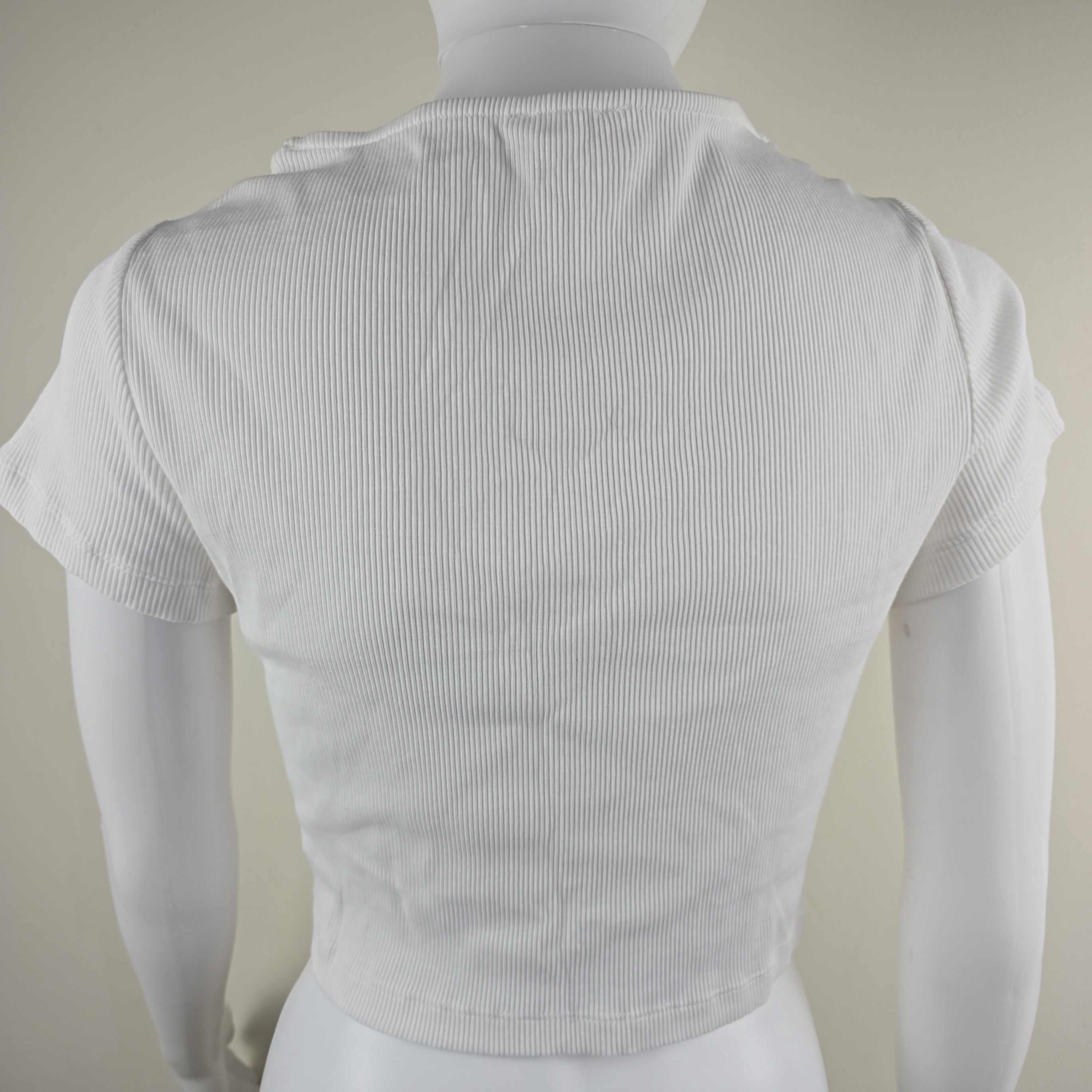 White top on a mannequin against a neutral background