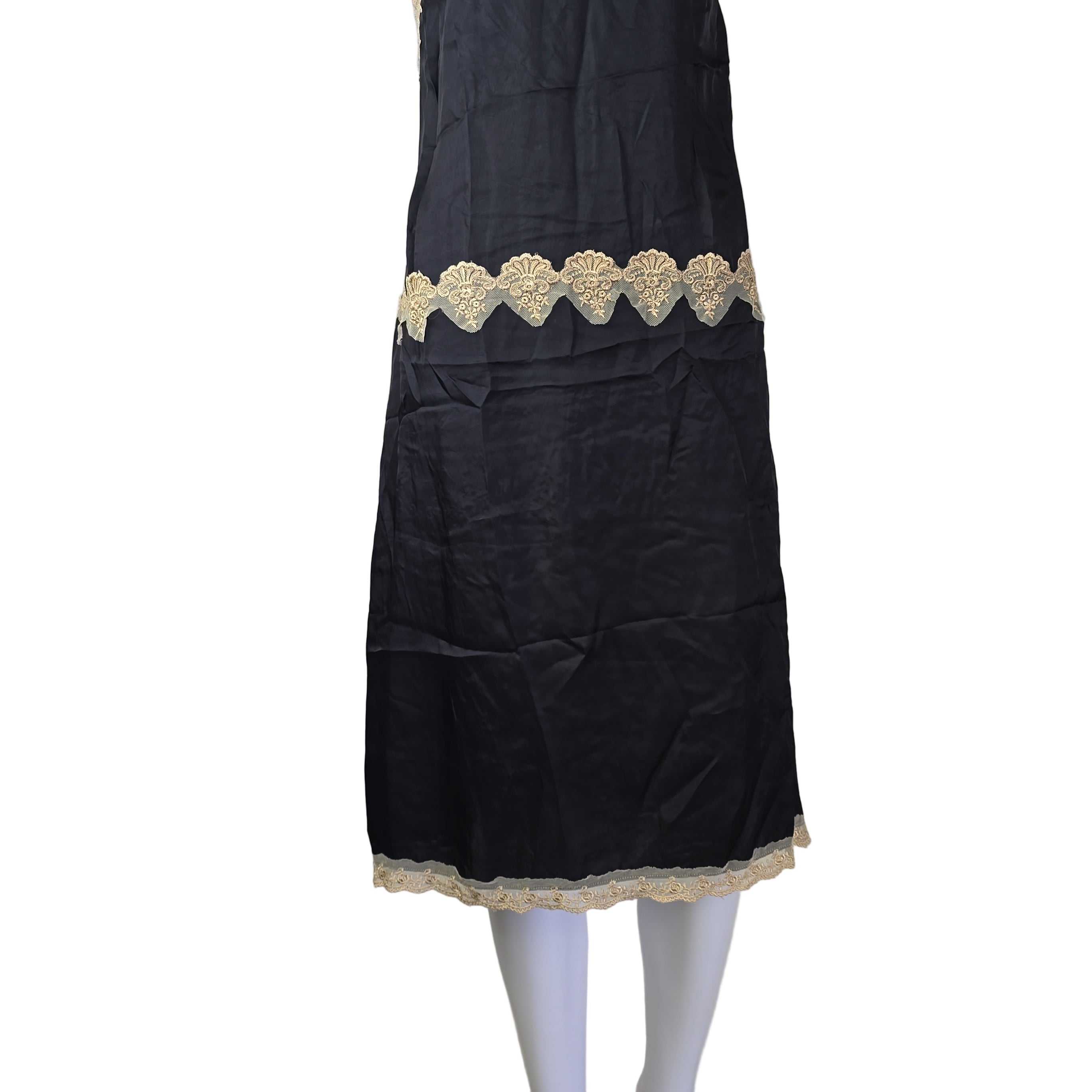Black fabric with gold lace trim on a white mannequin arm against a plain background