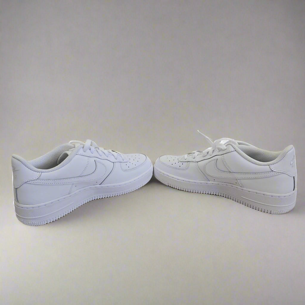 White sneakers leaning against a light-colored wall.
