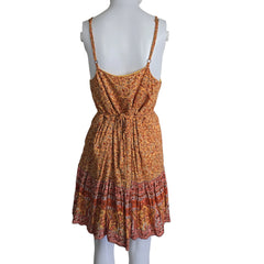 Mannequin wearing a pleated dress with a gradient of orange and red on a plain background