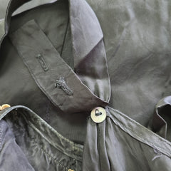 Close-up of a black dress with a button and brand logo