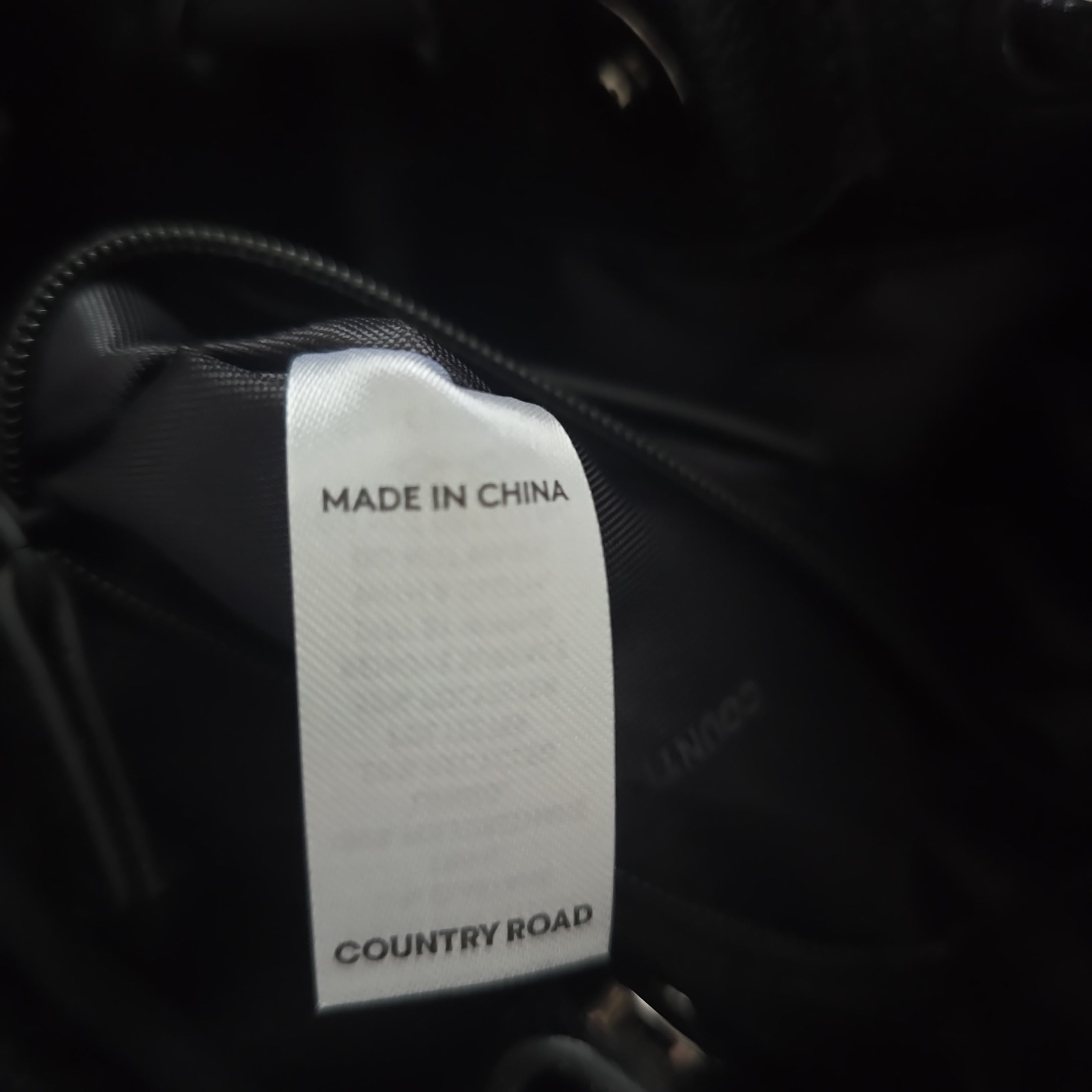 Clothing tag with 'Made in China' and 'Country Road' text on a black background