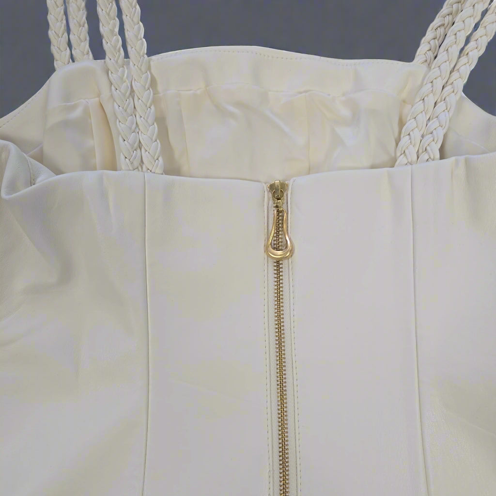 Close-up of a white dress with a gold zipper on a light gray background
