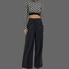 Woman wearing a black and white patterned top and black wide-leg pants on a white background