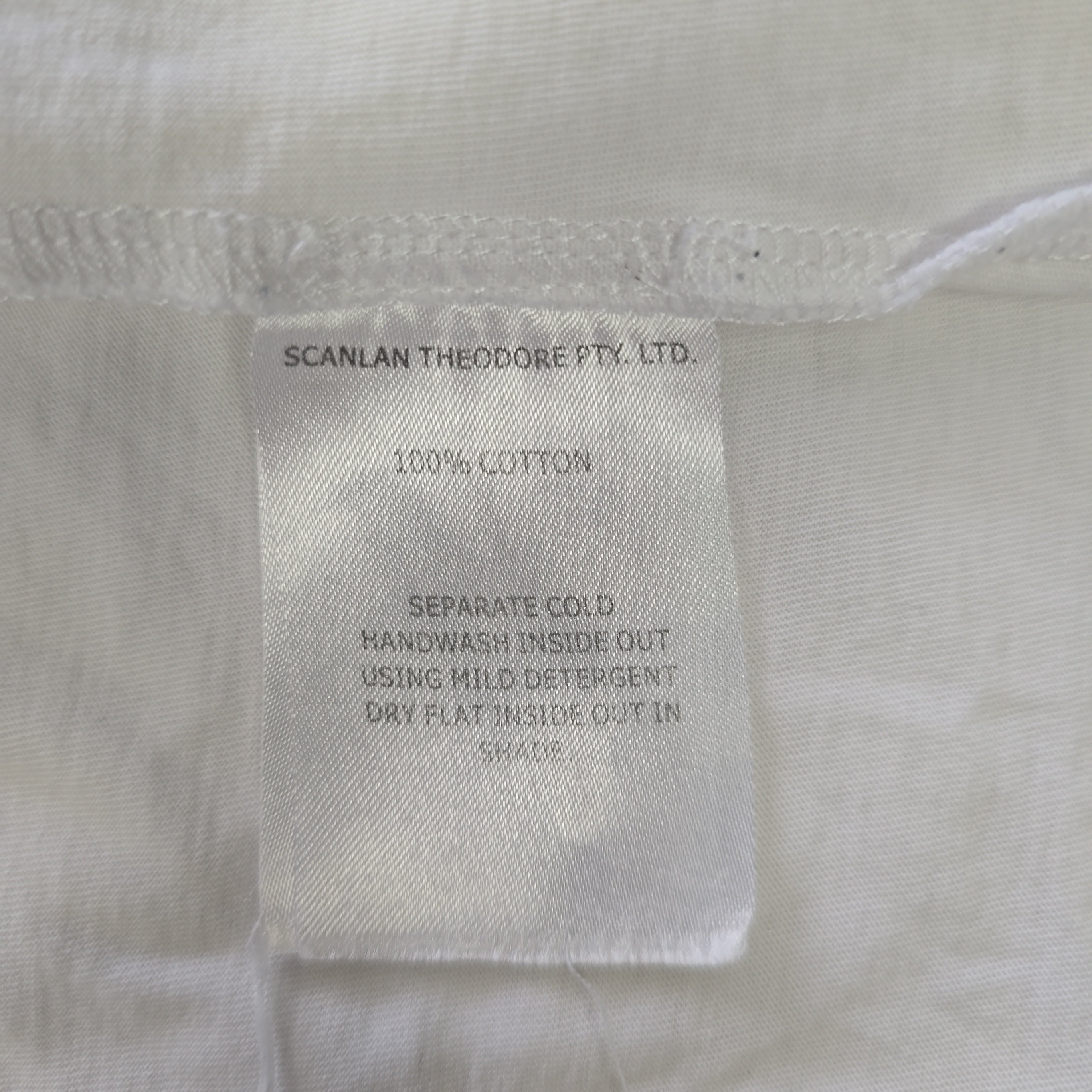 Fabric tag on a light-colored garment with text about care instructions and material composition.