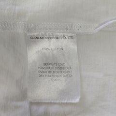 Fabric tag on a light-colored garment with text about care instructions and material composition.