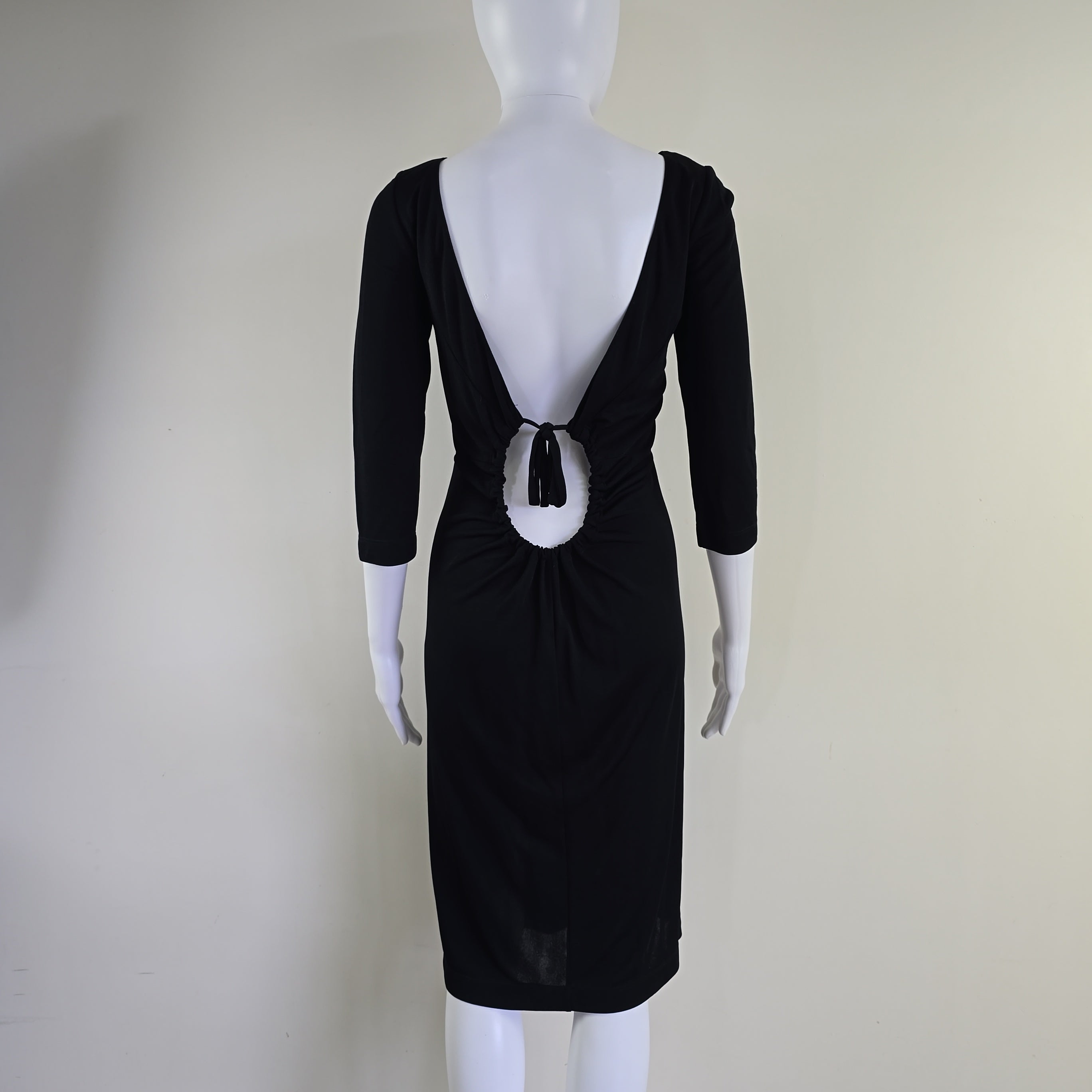 Black dress with a large bow on a mannequin against a plain background