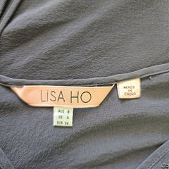Close-up of a gray garment with a 'Lisa Ho' label on a dark background