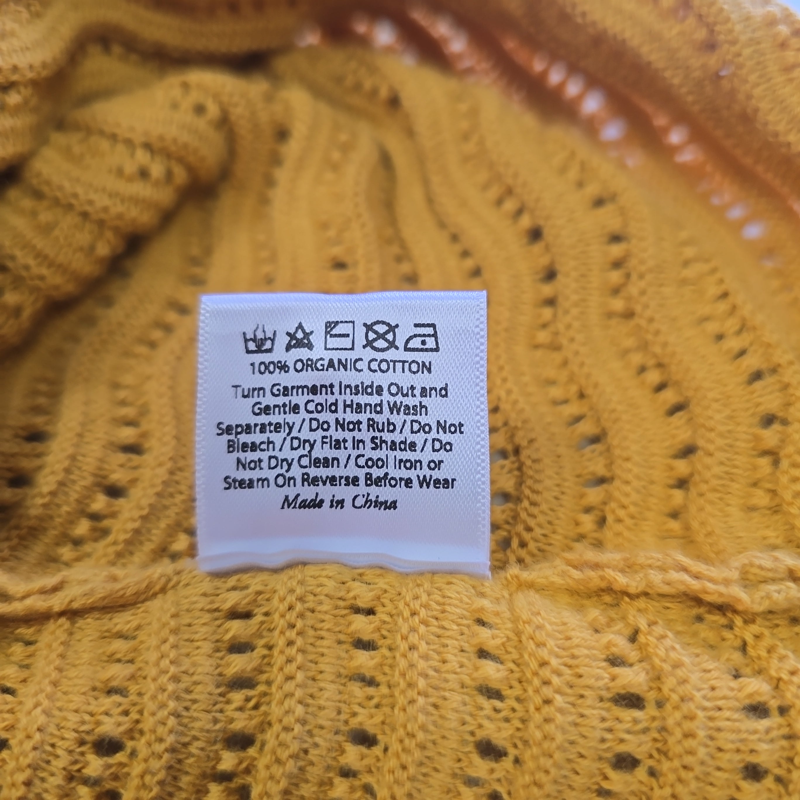 Close-up of a yellow knitted fabric with a label on it.