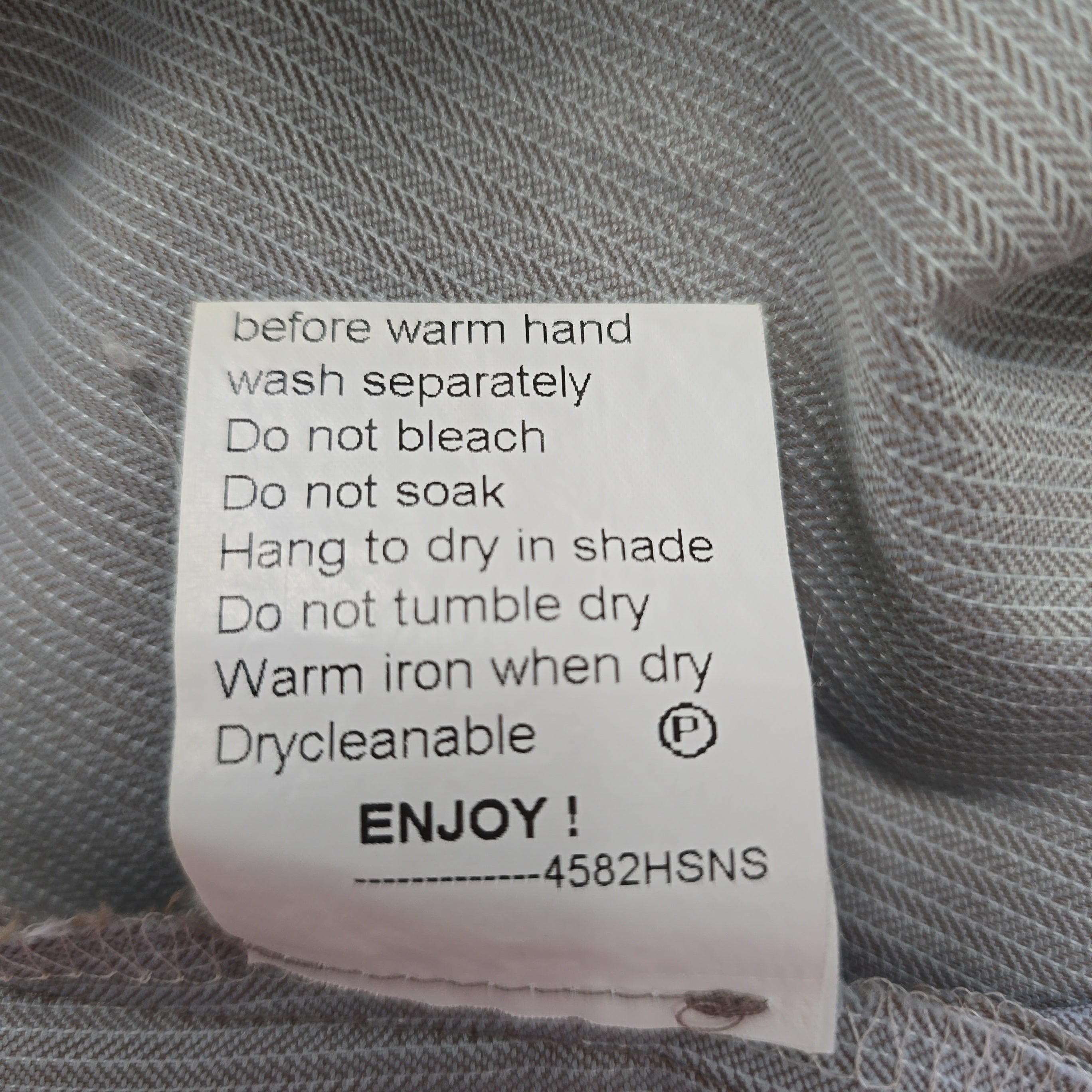 Clothing label with care instructions on a textured fabric background