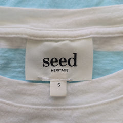 Close-up of a 'seed Heritage' label on a garment with a blue and white striped background.