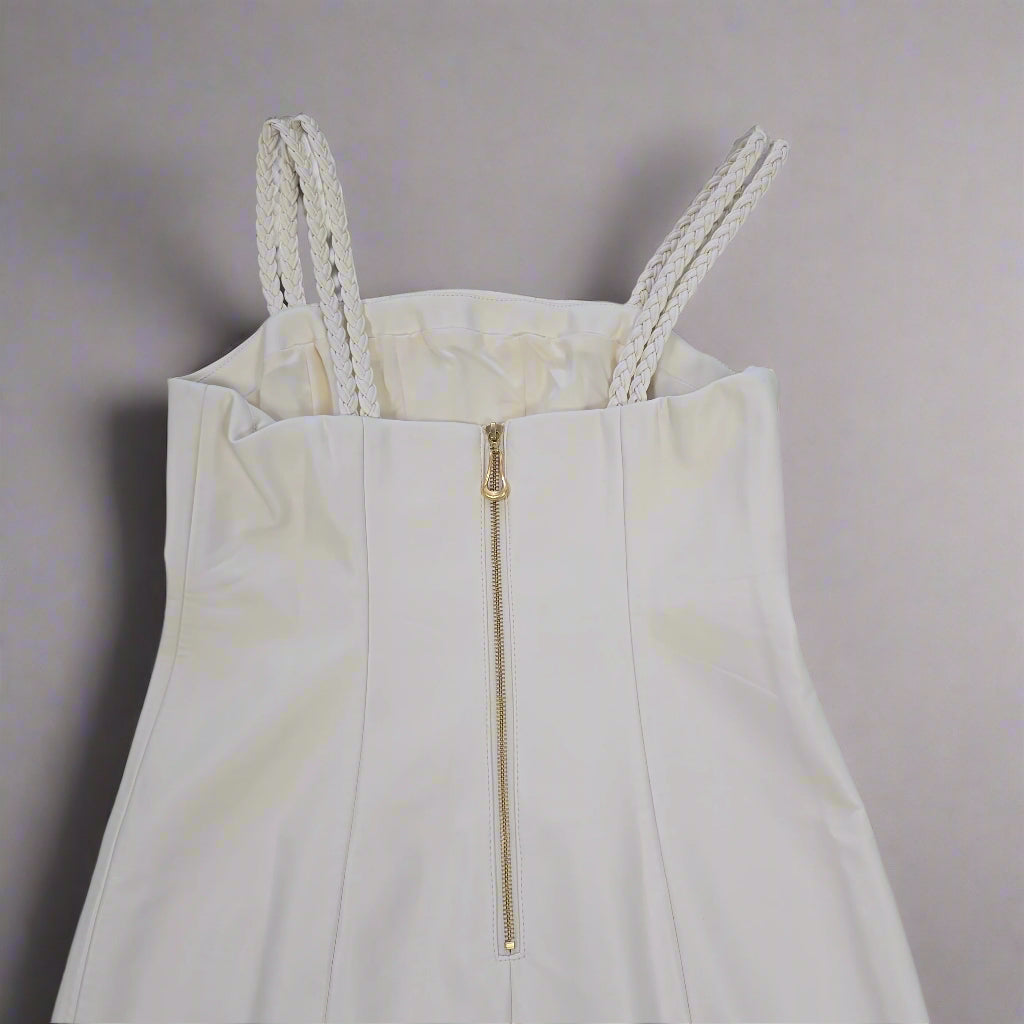 White dress with a gold zipper on a tiled floor