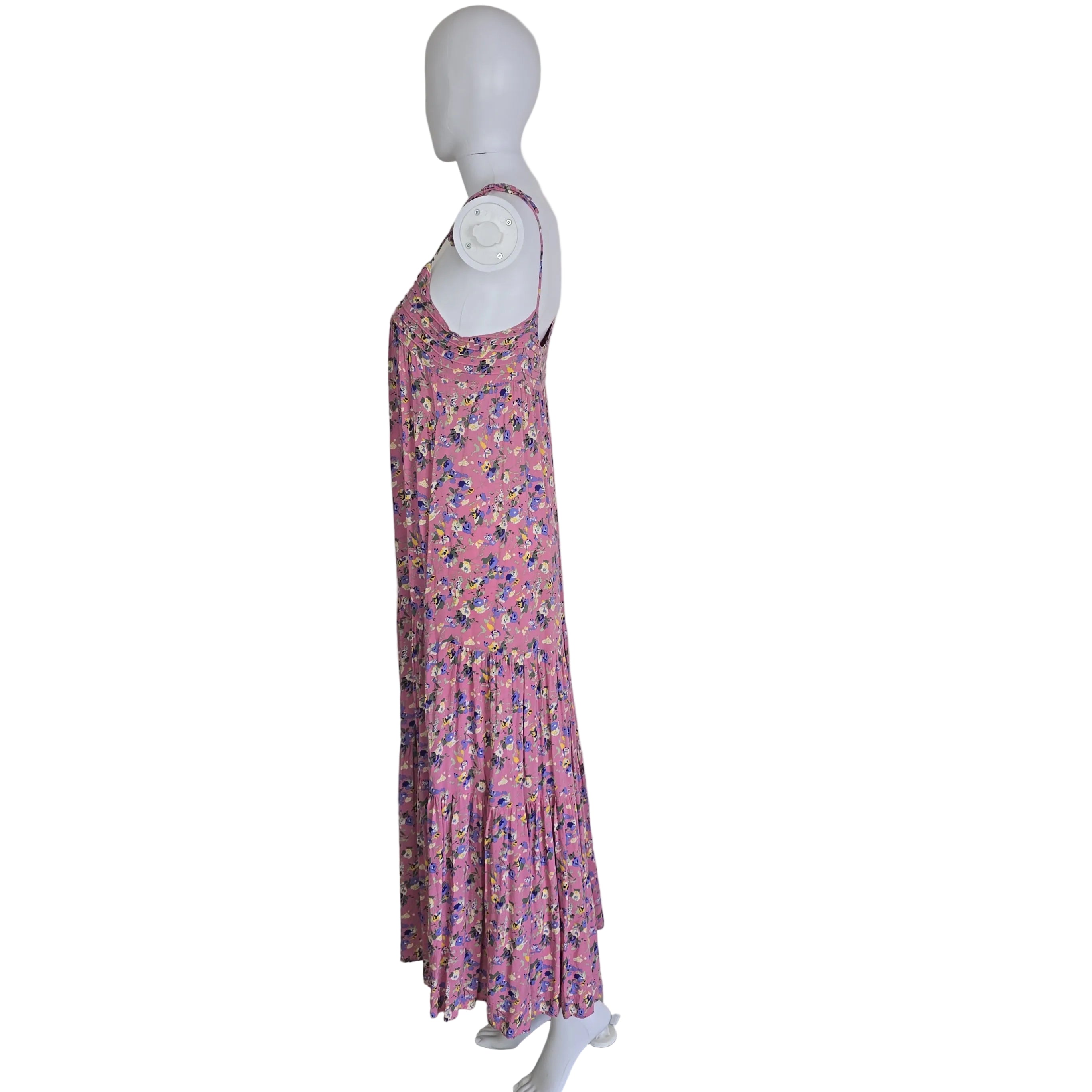 Folded pink floral dress on a mannequin against a white wall.