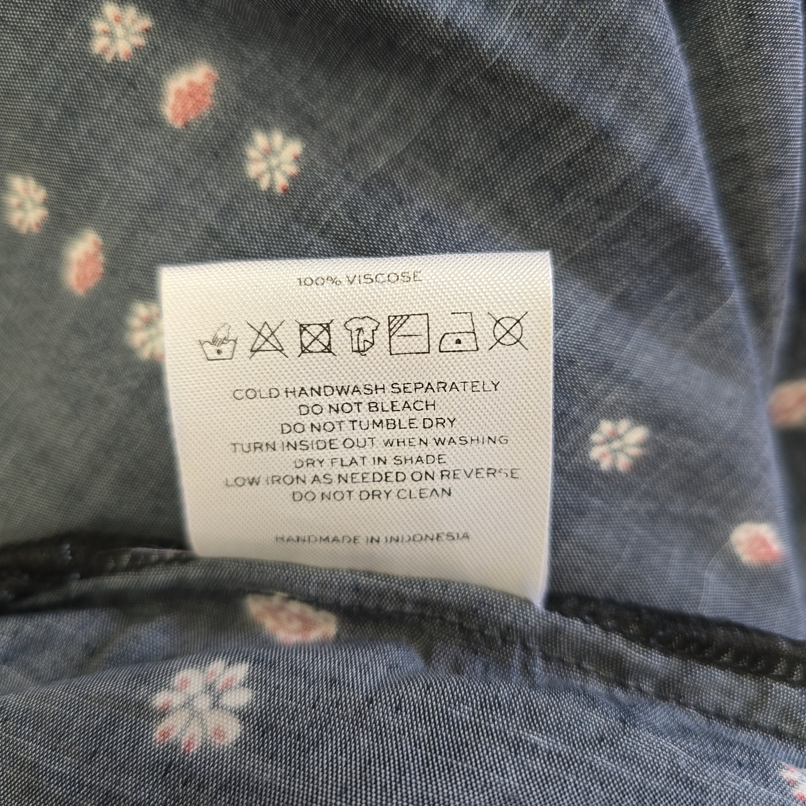 Clothing label on a floral-patterned fabric background