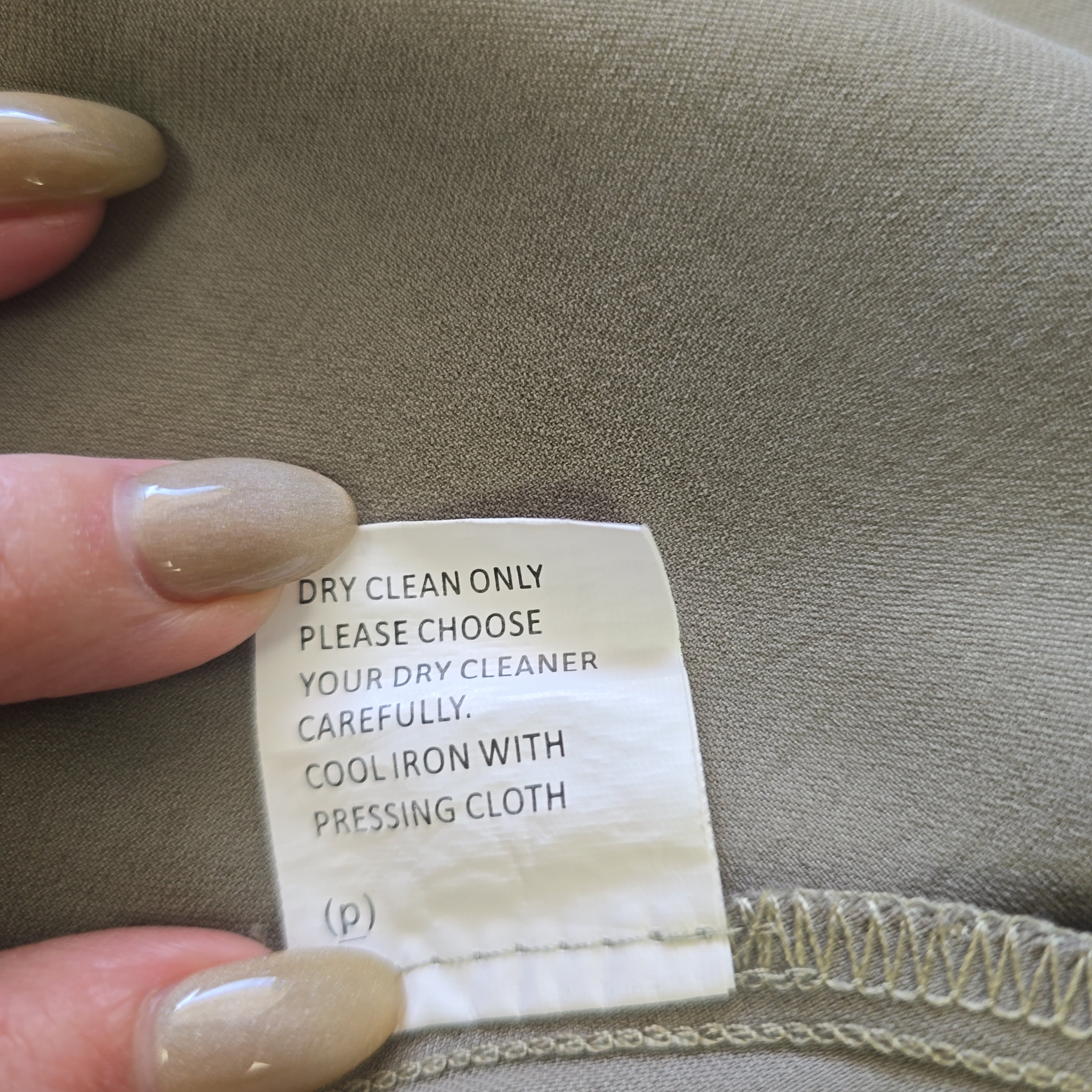 Clothing label on a fabric surface with a hand holding it.