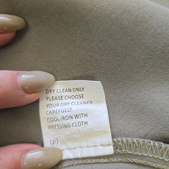 Clothing label on a fabric surface with a hand holding it.