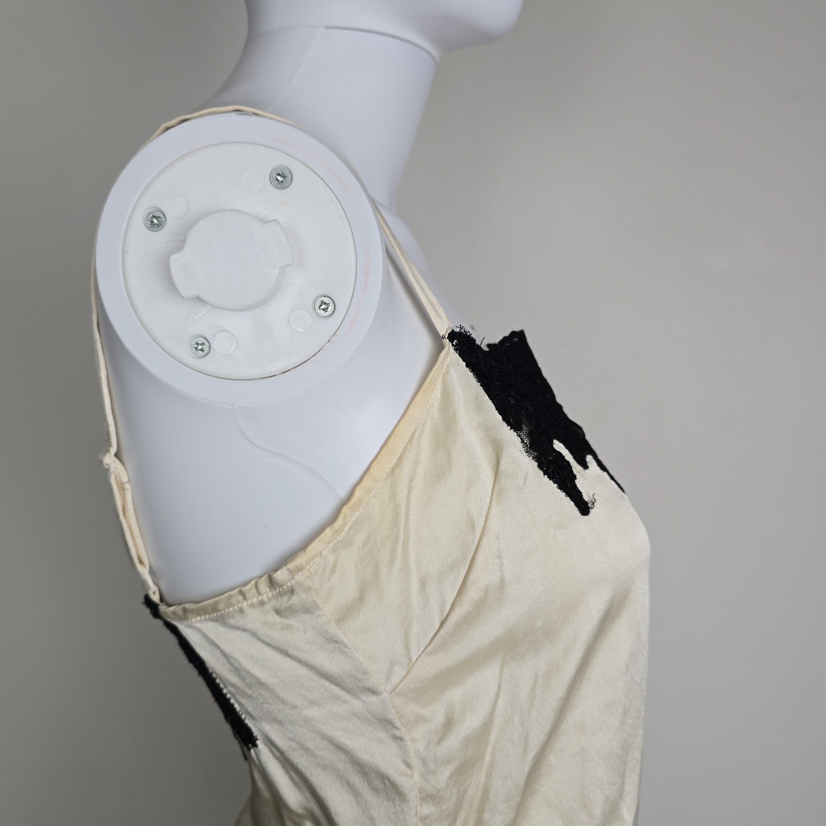 Mannequin wearing a white top with black lace details on a plain background