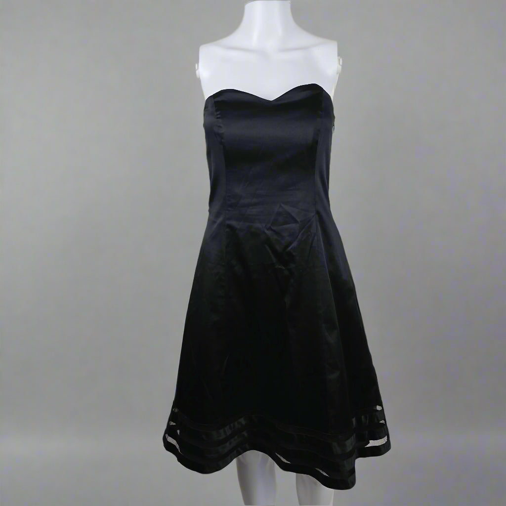 Black dress on a white mannequin against a plain background