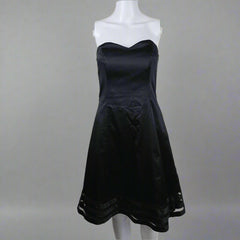 Black dress on a white mannequin against a plain background