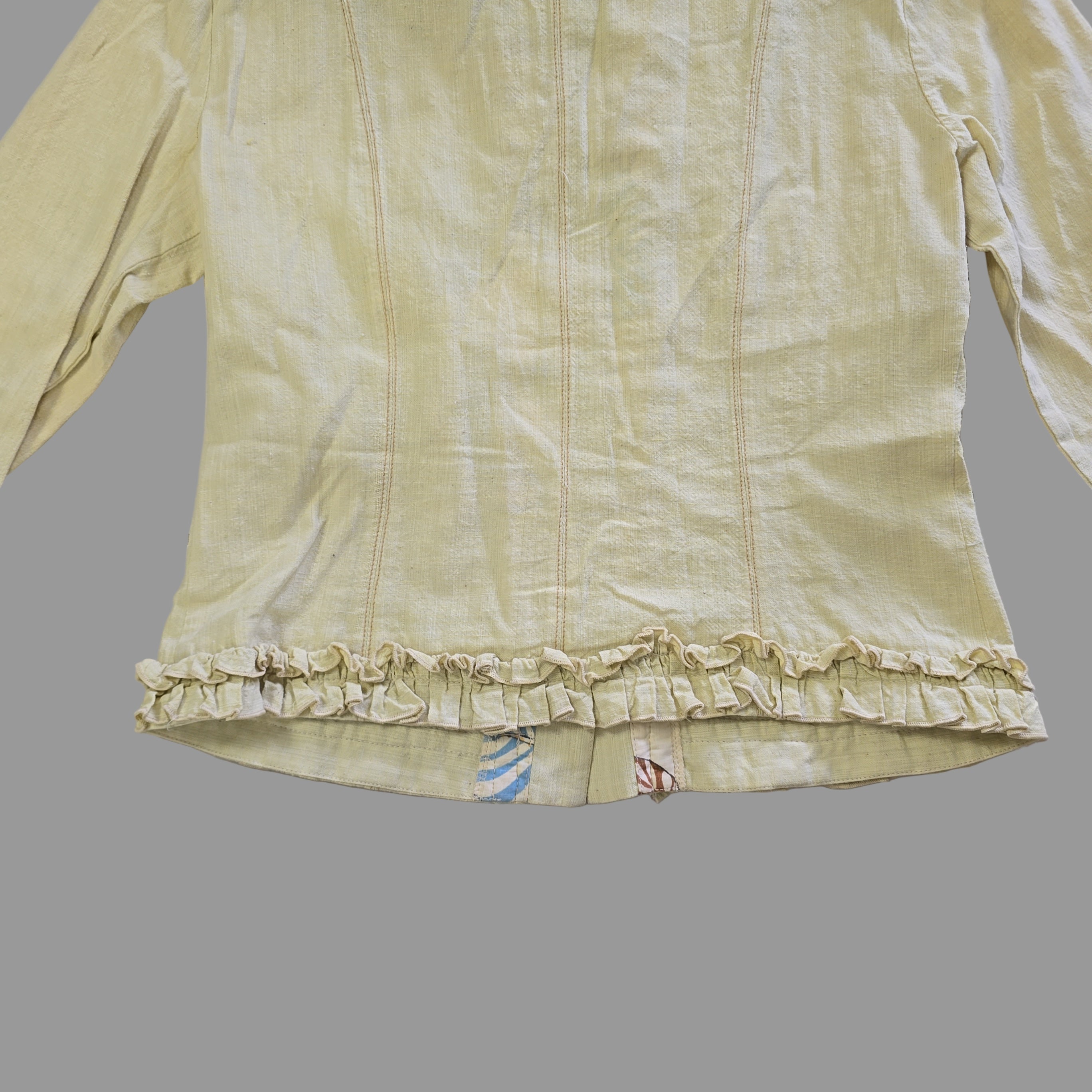 Light yellow jacket with frill details on a light background