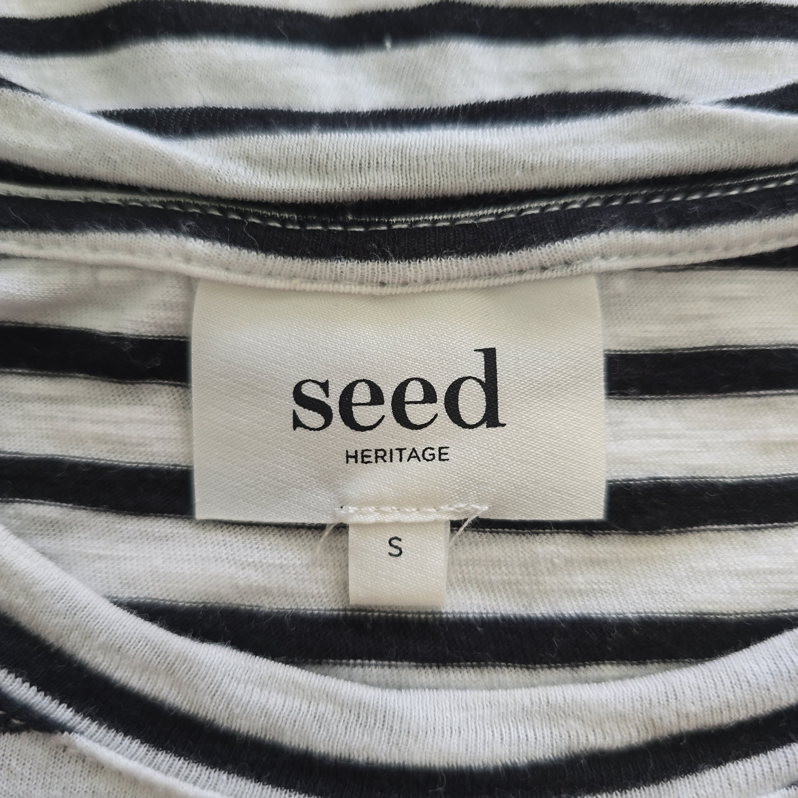 Close-up of a 'seed heritage' label on black and white striped fabric.