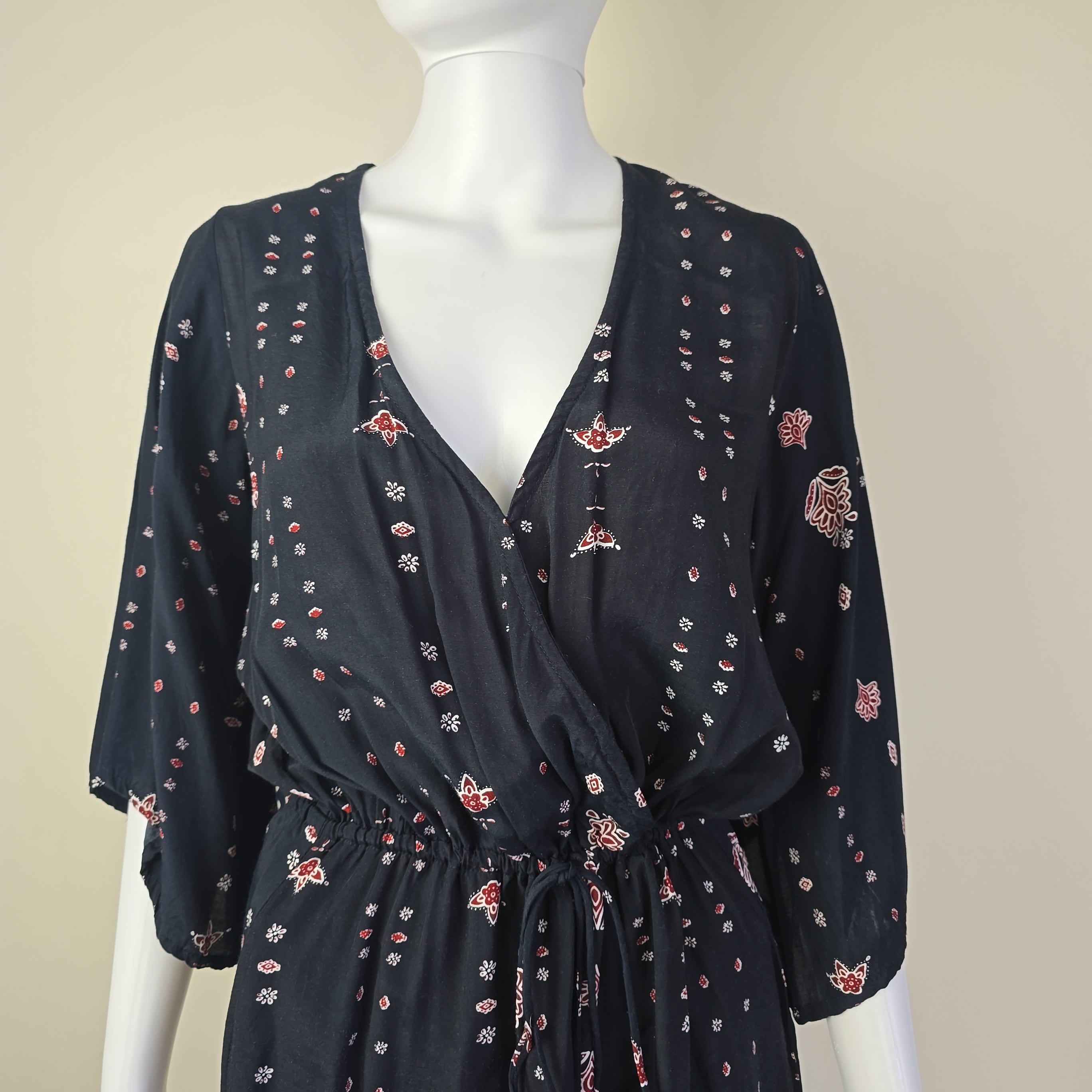 Black floral patterned top on a mannequin against a beige background