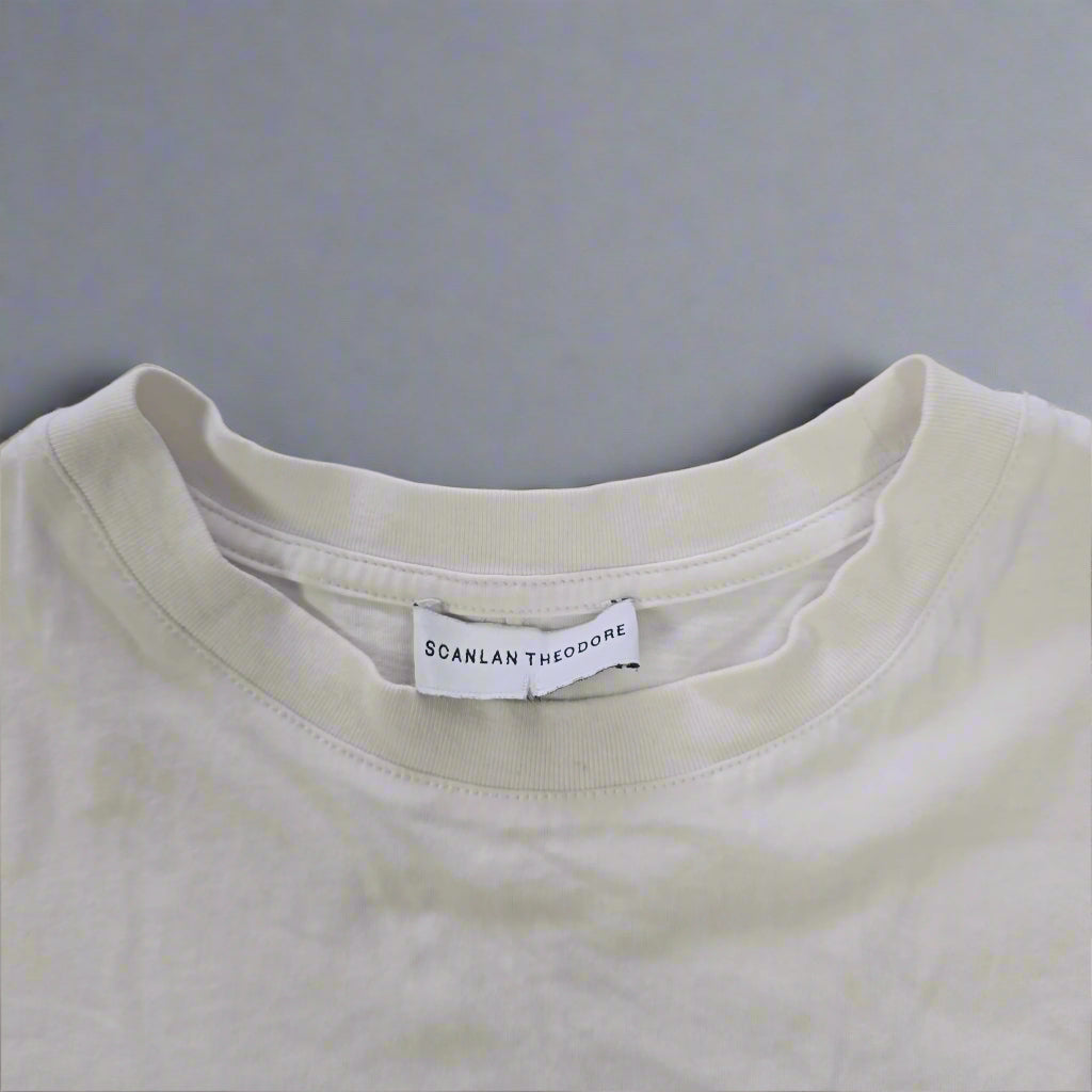 White t-shirt with a brand label on a tiled floor