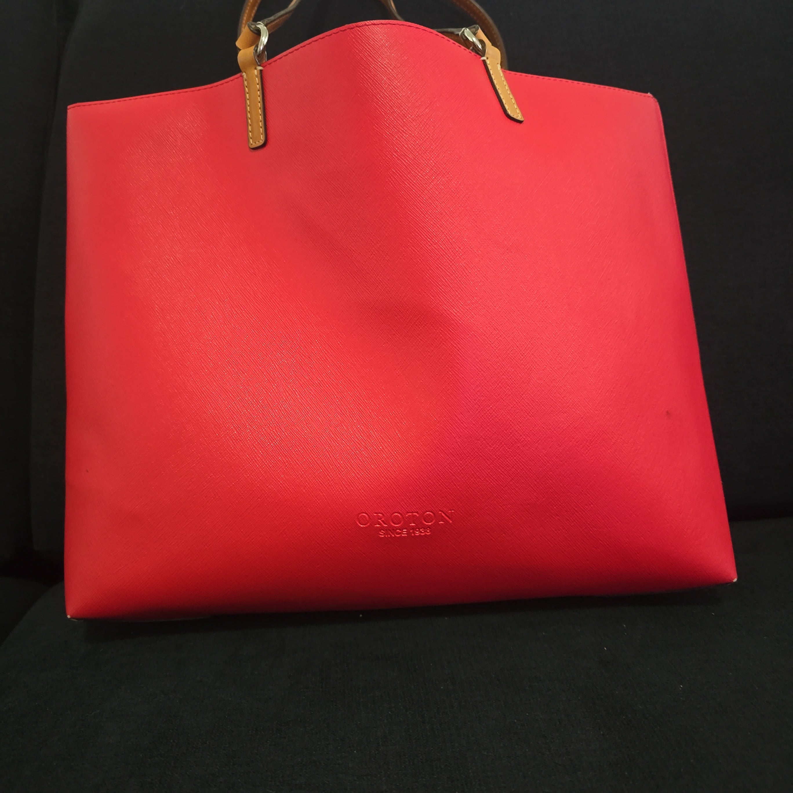 Red handbag with gold handle on a black background