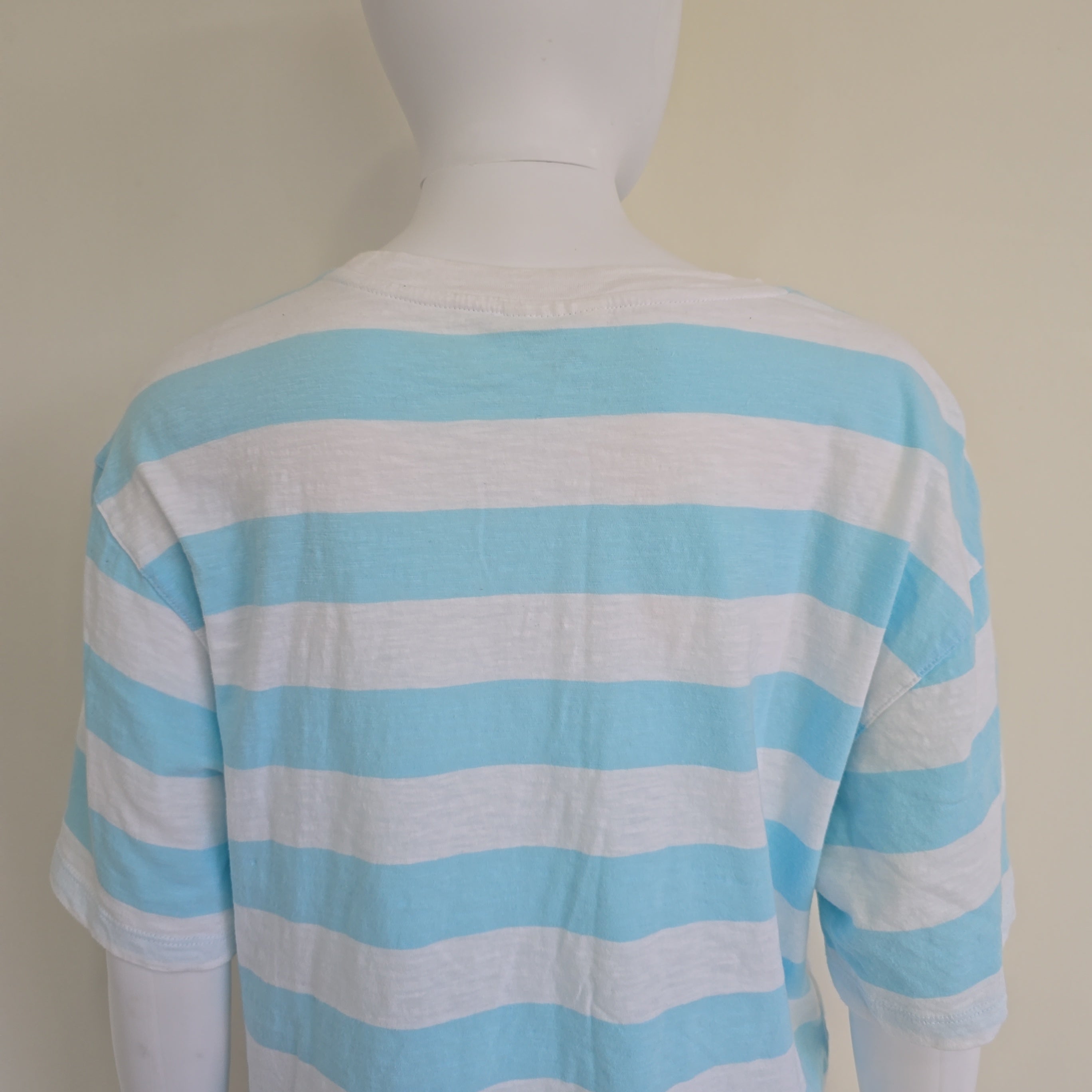 Mannequin wearing a blue and white striped garment against a plain background