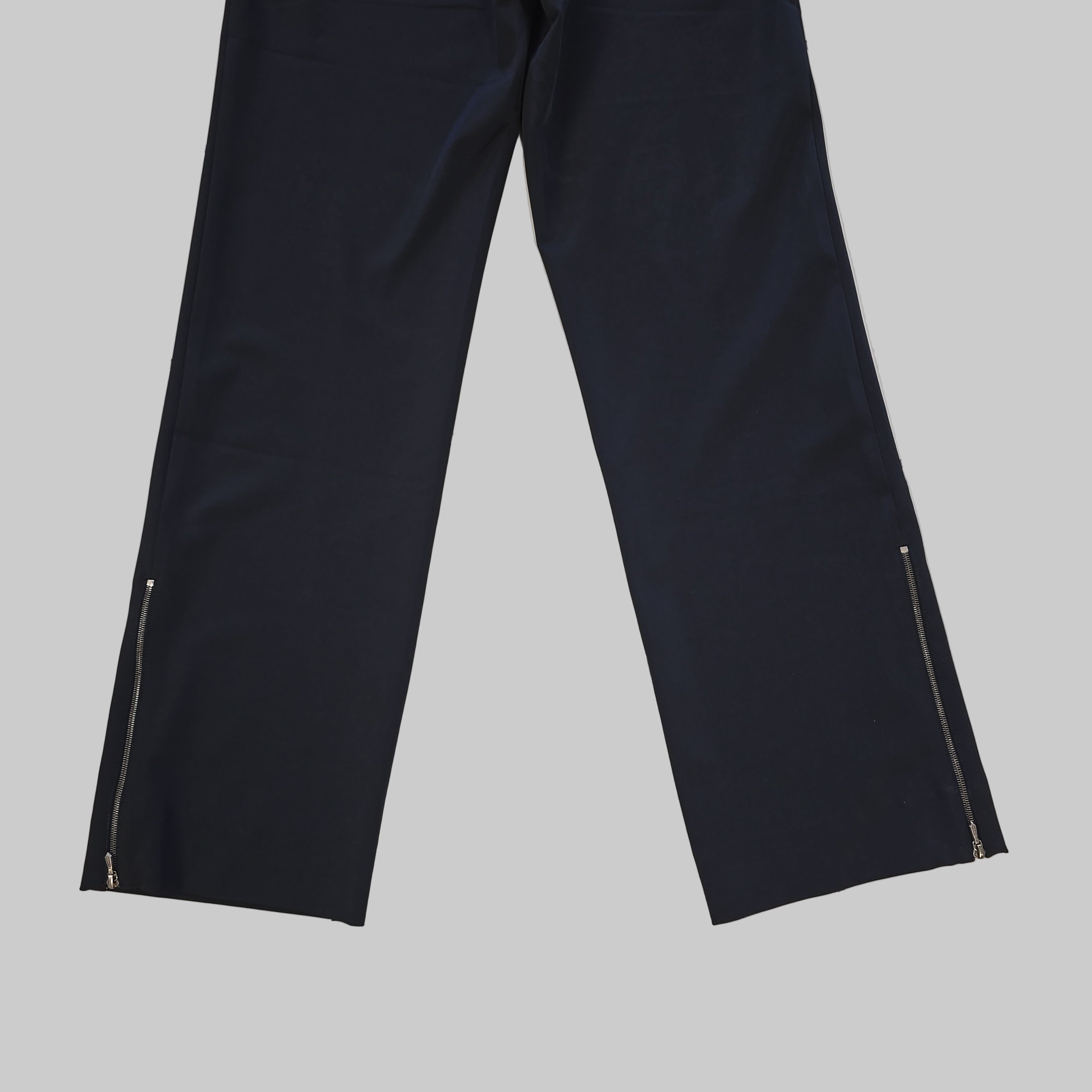 Two pairs of black pant legs on a tiled floor