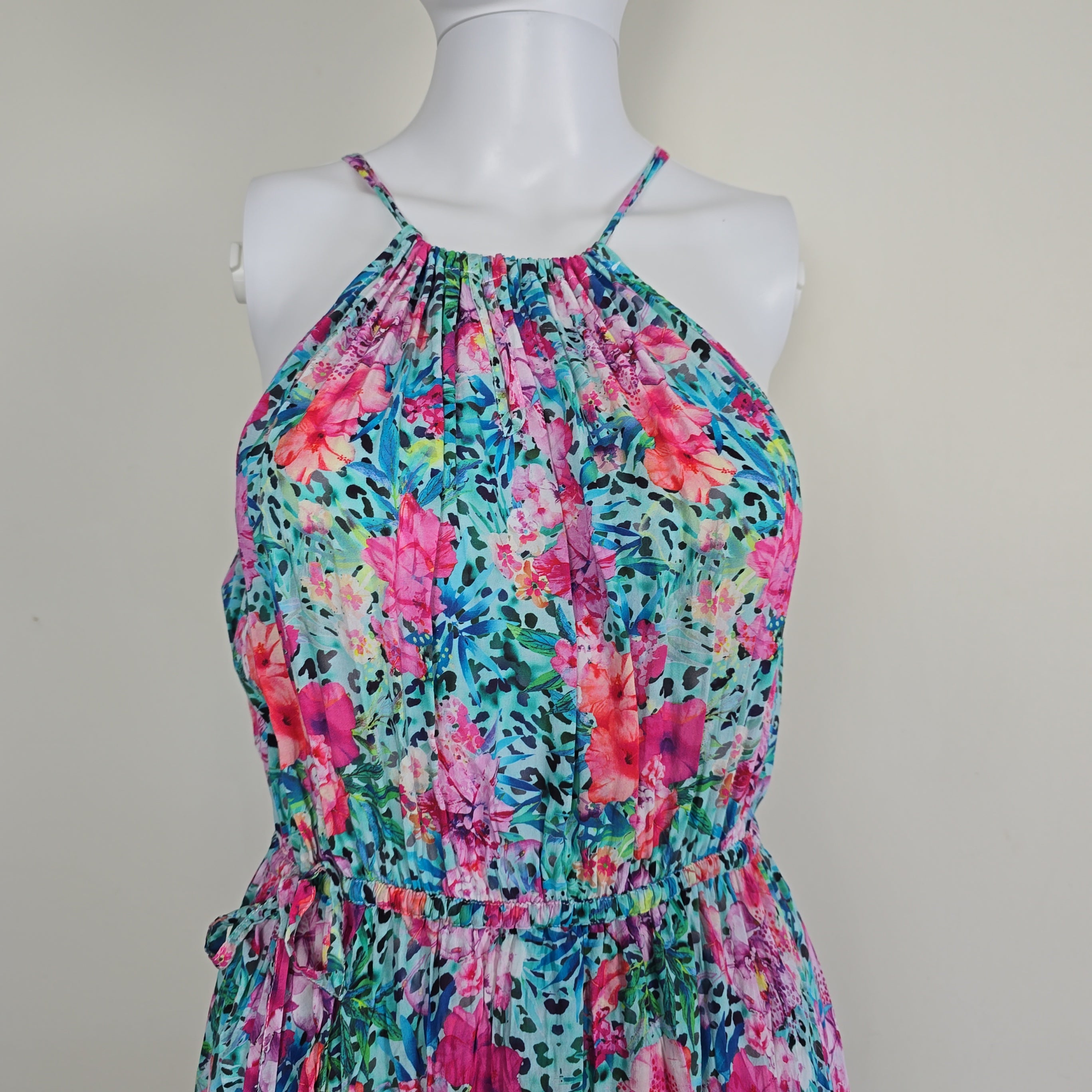 Multicolored floral dress on a mannequin against a plain background