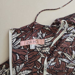 Brown and white patterned bag with 'LISA HO' label on a beige background