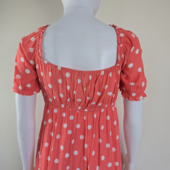 Red dress with white polka dots on a mannequin against a plain background