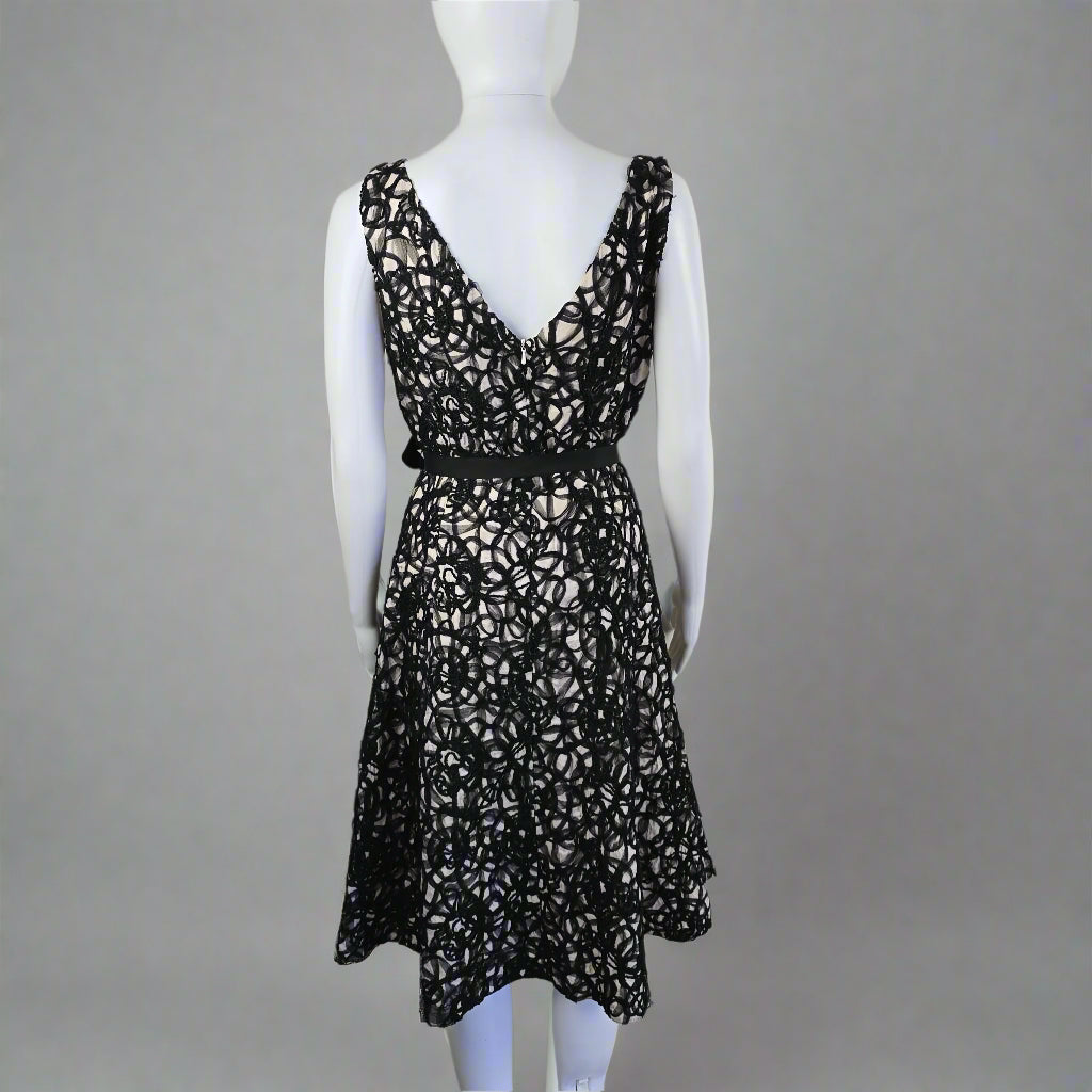 Black lace top on a mannequin against a plain background