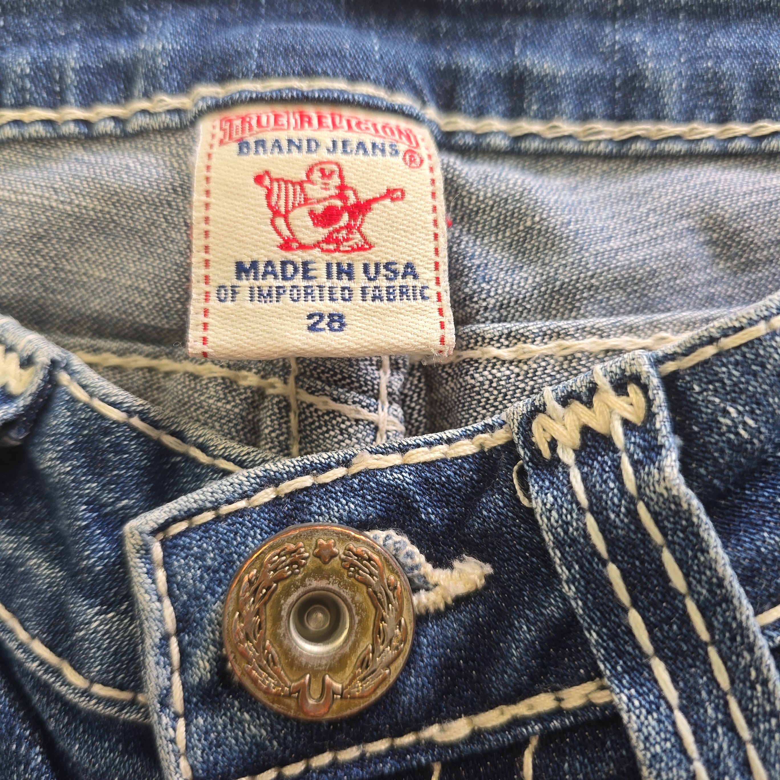 Close-up of brand label and button on denim shorts.